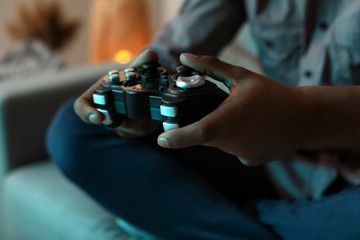 African-American teenage boy playing video game at home in evening, closeup