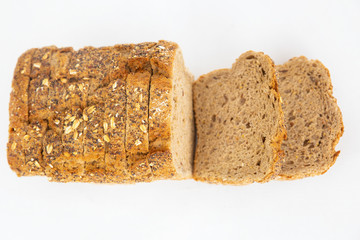 Homemade sliced cereal bread with oatmeal and seeds. Stack of brown loaf cut for sandwiches isolated on white background. Studio shot. Top view. Cooking and baking at home concept