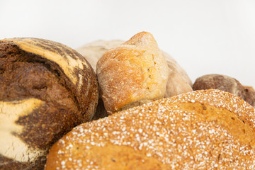 Close-up of wheat and rye breads with cereals. Tasty loafs and buns isolated on white background. Studio shot. Selective focus. Side cropped view. Cooking and baking at home concept