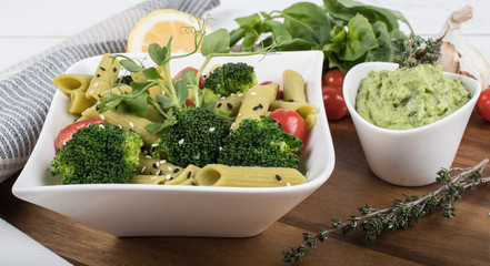 Gluten-free fresh cooked penne pasta from green peas isolated on wooden board. basil