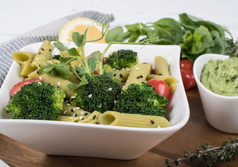 Gluten-free fresh cooked penne pasta from green peas isolated on wooden board. basil