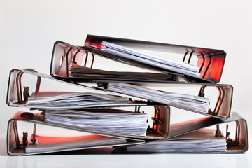 Heap of office folders with archived paperwork in red light