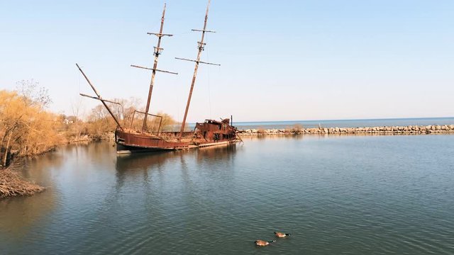 Drone zoom out from shipwreck with gees landing in water