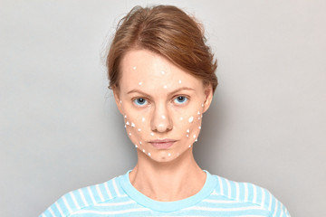 Portrait of serious girl with white drops of face cream on skin