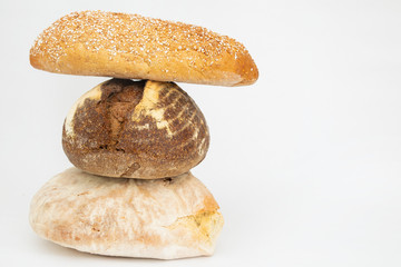 Stack of three wheat and rye breads with cereals and seeds. Fresh different loafs and pastry isolated on white background. Studio shot. Side view. Homemade food and nutrition concept