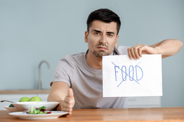 Young man with anorexia refusing to eat food at home