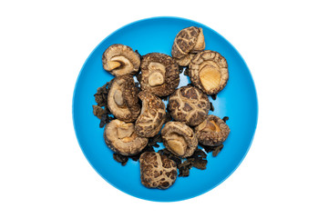 Top view of dried Shiitake Mushroom on blue plate. Isolated on white background