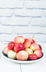 Ripe apples on a plate on a light background. The harvest of autumn apples.