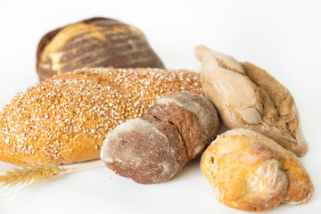 Crusty pastry made of wheat and rye flour. Delicious loafs, buns, breads isolated on white background. Studio shot. Selective focus. Side cropped view. Homemade bakery and nutrition concept