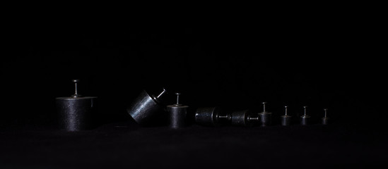 Different weights are arranged in descending order in a dark copy space background. Product photography.