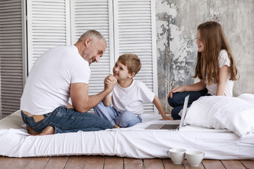 Fototapeta premium Father and son fight in their arms, and his daughter watches them. They are home on self-isolation.
