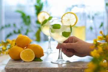 Citrus iced lemonade in pitcher and lemons glasses with lemon slice decoration and on marble table hand with cocktail
