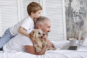 Father and son watch cartoons on a laptop lying on the bed.