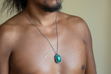 Male chest wearing elegant necklace with natural mineral gemstone