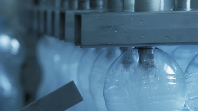 Automatic conveyor line for bottling mineral water and covering caps on plant. Industrial production artesian water from natural well in plastic bottles. Factory of manufacturing fresh spring water.