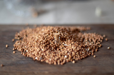 Picture with soft focus of tiny corked glass jar with buckwheat on dark background from scattered buckwheat.