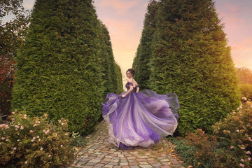 A beautiful young girl in a lilac dress running down the alley of the autumn park. Romantic evening...