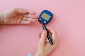 Woman pricks her finger with a lancelet to measure blood glucose levels. Diabetes, gestational diabetes mellitus concept.