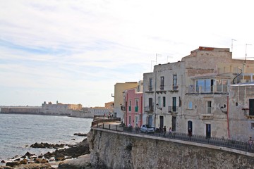 Sicily, Syracuse, old classical buildings on the seashore in Ortigia, street on the shore, buildings, sea and volcanic rocks