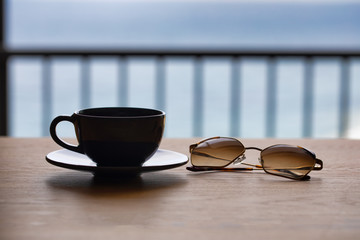 Breakfast in a Cafe on the Beach. White Coffee Cup on the Wooden Beach Table. cofee with sunglasses and news paper. beach background. holiday background. restaurant open. cafe coffee background