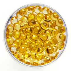 Transparent round capsules of vitamins - Fish oil pills close-up. Small gold-yellow balls on a white background. Concept of treatment and prevention of health. 