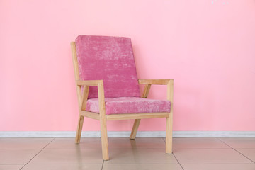 Comfortable armchair near color wall in room