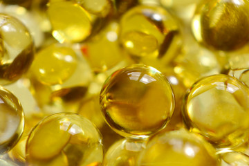 Fish oil pills. Transparent round capsules of vitamin as an abstract background. Small gold-yellow...