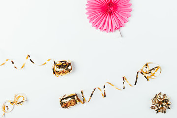 Pink paper birthday party decoration next to golden bow and ribbons