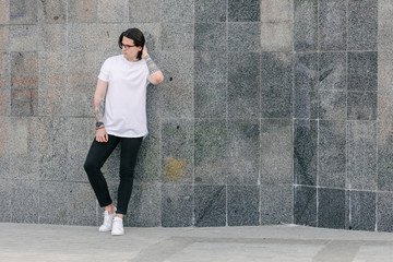 Hipster handsome male model wearing white blank t-shirt with space for your logo or design in casual urban style