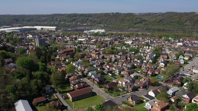 A slowly moving forward aerial establishing shot of a typical Pennsylvanian downtown district. Ohio River, churches, homes, and factories in the distance. Pittsburgh suburbs. Flown with FAA authorizat