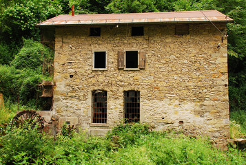 Fototapeta na wymiar An old abandoned mill near Salino in Friuli, north east Italy. It has a water wheel mounted vertically on a horizontal axis. 
