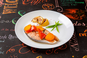 Salmon steak in a plate on a table in a restaurant