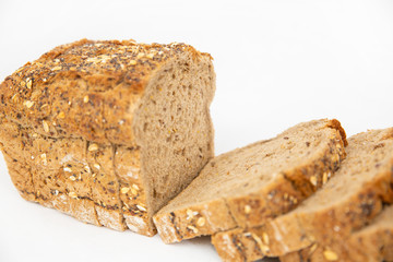 Close-up of sliced cereal bread with oatmeal and seeds. Pieces of brown loaf laying together isolated on white background. Studio shot. Angled cropped view. Homemade bakery and cooking at home concept