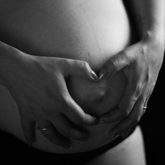 Barriga de mujer embarazada con cicatriz haciendo un corazón con las manos
