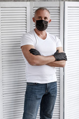 An adult man in a black medical mask and black gloves.