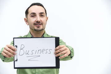 Brunette bearded man holding paper holder with word business writen on it, looking with comical face expression.