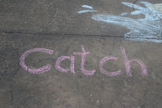Chalk art on a driveway.  The word "catch".