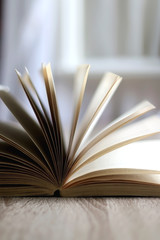 Open book on a table by the window. Selective focus.