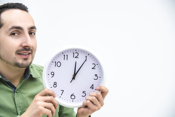 Cropped portrait of man in green waiting, holding clock over white background.