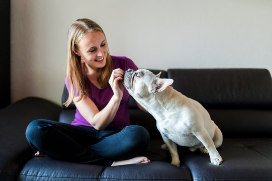 Woman is sitting with french bulldog on couch