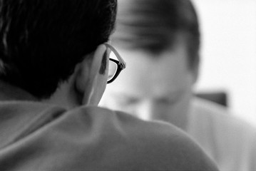 Cropped image of businessman wearing eyeglasses sitting with colleague at office