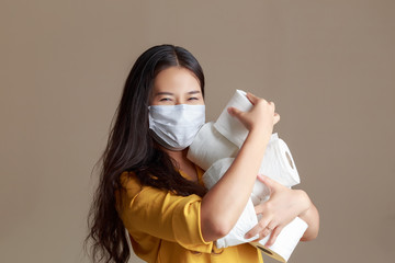 Young Asian woman wearing mask and yellow shirt. Asian woman holding tissue toilet paper during Coronavirus outbreak or Covid-19, Concept of Covid-19 quarantine.