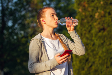 Young female runner, athlete resting after jogging in the city street in spring sunshine. Beautiful caucasian woman, fit and cheerful. Concept of sport, healthy lifestyle, movement, activity.