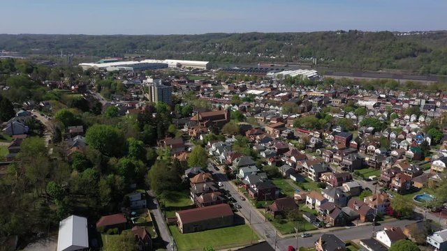A summer cinematic orbiting aerial establishing shot of a the downtown area of small Pennsylvania town. The Ohio River in the distance. Pittsburgh suburbs. Flown with FAA authorization.  	