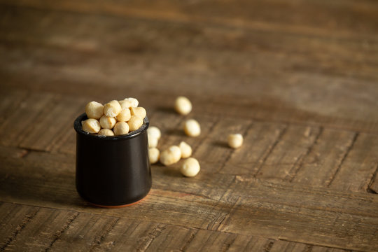 Macadamia nuts in a rustic black jar on a wooden table