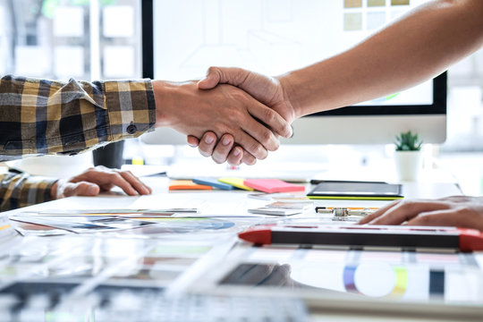 Team of young Interior graphic designer shaking hands after working sketching on color swatch, discussing of house project at modern office, creative work place inspiration and imagine