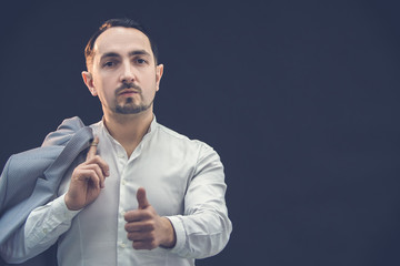 Well-dressed man in suit posing on black background, giving thumb up.