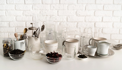 ceramic and glass cups and tableware on the table on white brick wall background