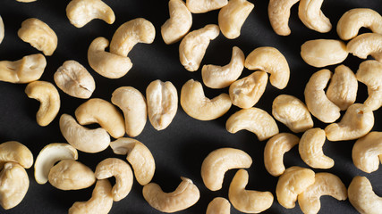 Top view of scattered cashews on a black background. Nuts for heart health, eyes and good for skin. Healthy nuts.