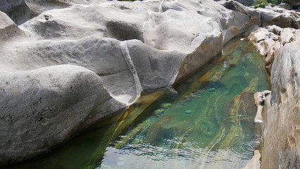 Fototapeta premium vom Wasser geformte Felsen mit smaragdgrünem Wasser im Verzasca Tal, einem Seitental am Lago Maggiore